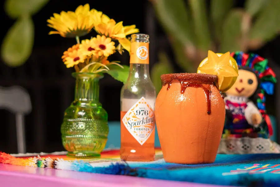 Cantarito junto a flores y muñeca mexicana